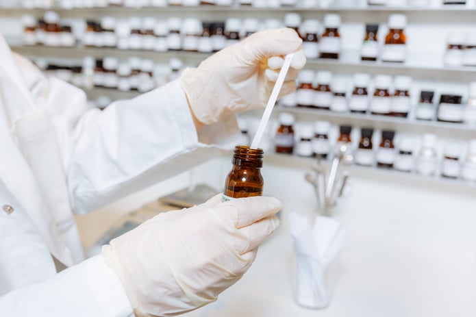 Gloved hands holding amber bottle and putting a white strip in it